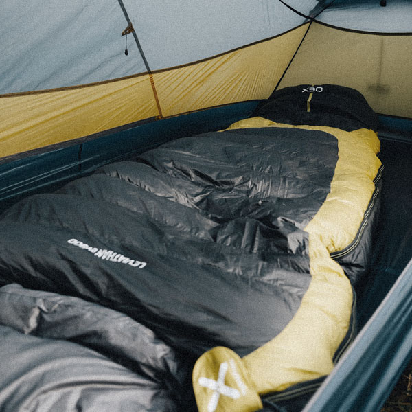 An image of a yellow and black sleeping bag set up inside a tent.