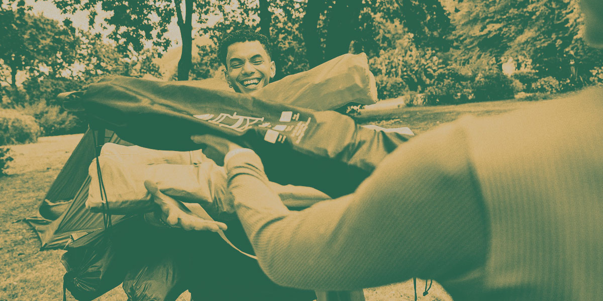 A person carrying lots of different coloured camping chairs, packed away in their carrying bag.