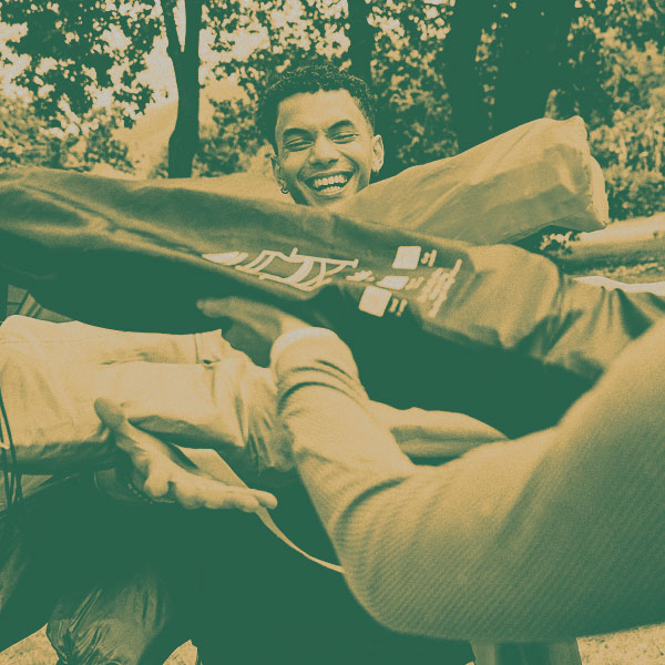 A person carrying lots of different coloured camping chairs, packed away in their carrying bag.