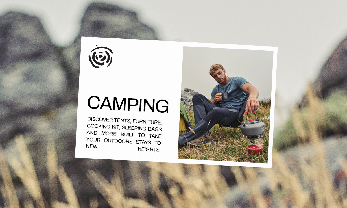 A man sat outside his tent cooking on a camping stove.