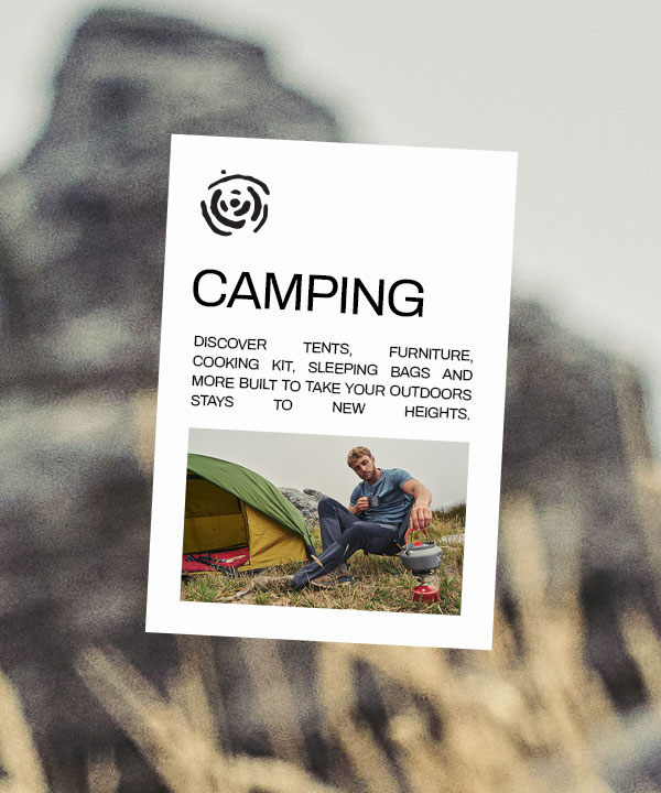 A man sat outside his tent cooking on a camping stove.