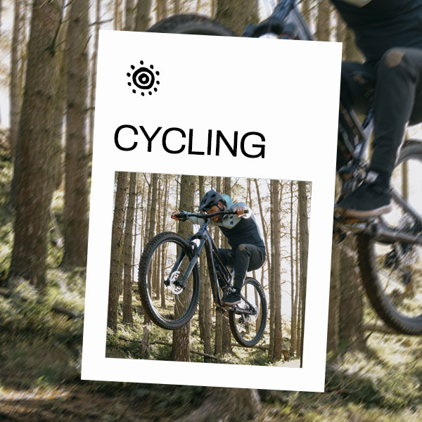 A biker making a jump on a forest downhill mountain bike trail.