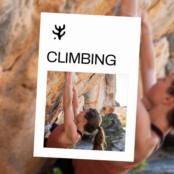 A woman holding her weight to rest whilst climbing on a rock face.