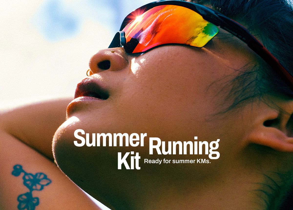 Close-up of a person wearing reflective wraparound sunglasses, head tilted back in bright sunlight, with a small arm tattoo visible; bold overlay text reads “Summer Running Kit” with the subtitle “Ready for summer KMs.”