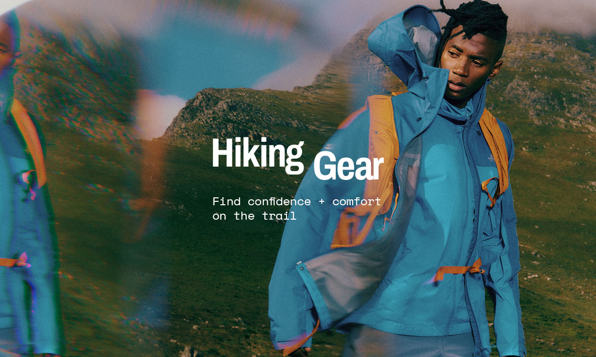 Hiker wearing a blue waterproof jacket and orange backpack standing in mountainous terrain with ‘Hiking Gear’ and ‘Find confidence + comfort on the trail’ text overlay.