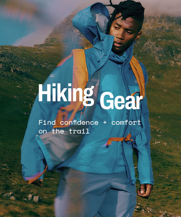 Hiker wearing a blue waterproof jacket and orange backpack standing in mountainous terrain with ‘Hiking Gear’ and ‘Find confidence + comfort on the trail’ text overlay.