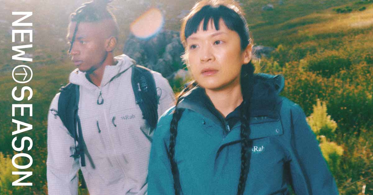 Man and women wearing waterproof jackets with a grassy field in the background