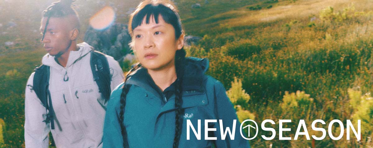 Man and women wearing waterproof jackets with a grassy field in the background
