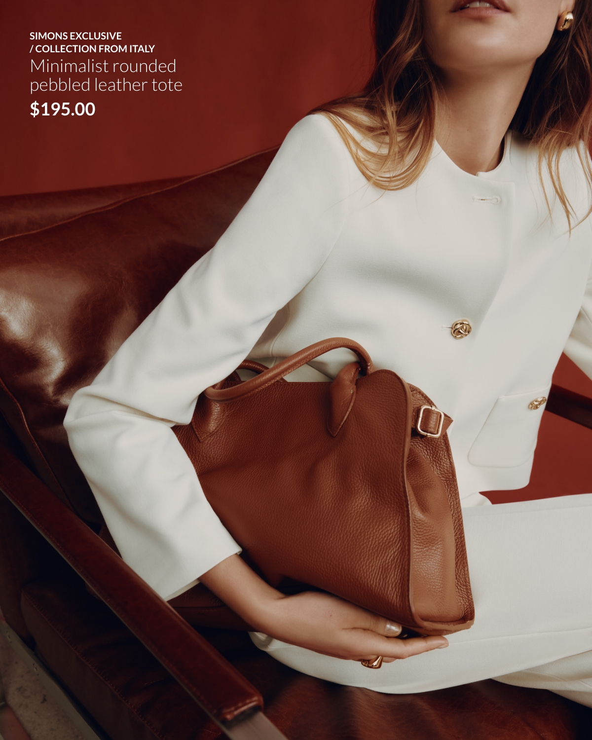 Woman sitting down wearing an all-white outfit and a minimaliste rounded pebbled leather tote from our collection from Italy at 195$