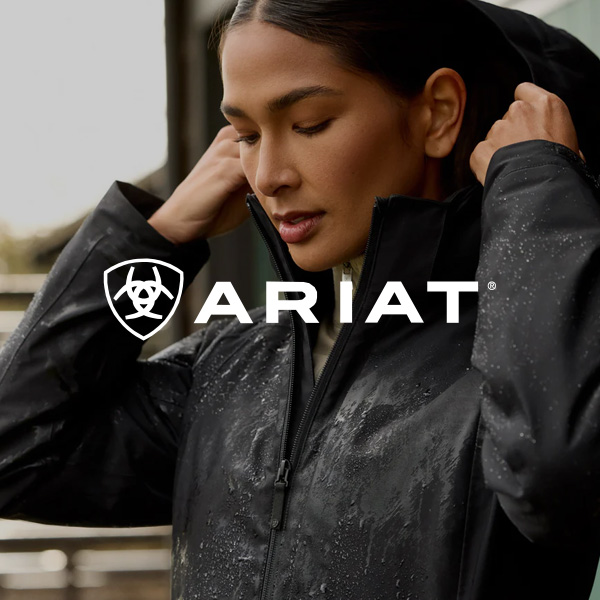 Person adjusting the collar of a black waterproof jacket with visible rain droplets; Ariat logo displayed across the centre.