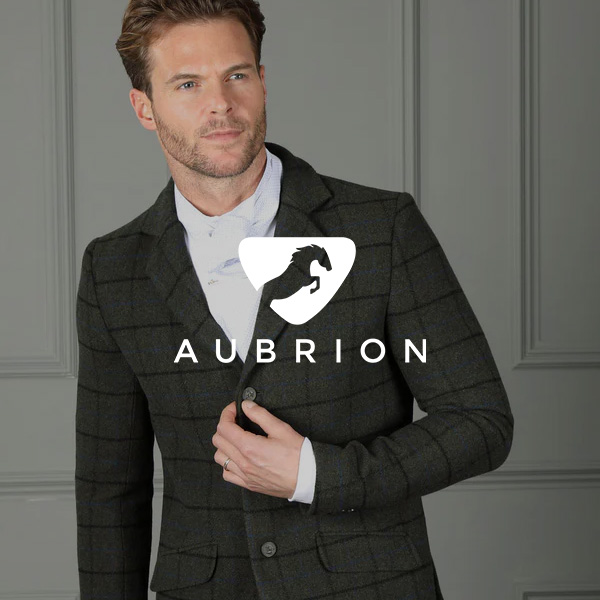 Person wearing a tailored dark check riding jacket adjusts the front button against a paneled wall; Aubrion logo displayed prominently.