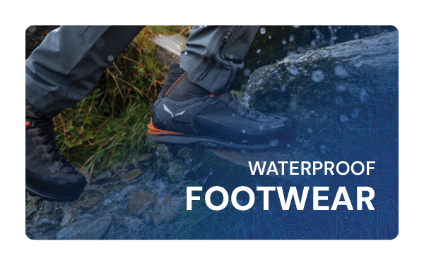 WATERPROOF FOOTWEAR. A man walks on a rainy trail wearing Salewa Men's Crow GORE-TEX Mountaineering Boots in Grey. 