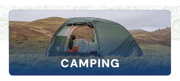 CAMPING. Image depicts a woman lying down in a Big Agnes Copper Spur UL 2 2-Person tent with both doors open, admiring the scenery in front of her