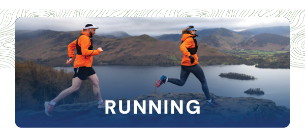 RUNNING. Two runners run along a cliff side, looking out across a loch. They wear bright orange running jackets, running shoes and hydration trail vests. 