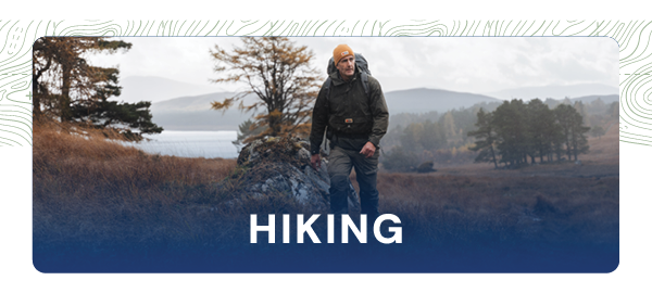 HIKING. Image depicts a hiker walking through a glen. He wears  a green hiking jacket, yellow beanie and a technical hiking rucksack. 