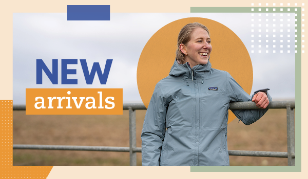 NEW ARRIVALS. A woman leans against a railing, wearing Patagonia Women's Torrentshell 3L Rain Jacket in Light Blue.