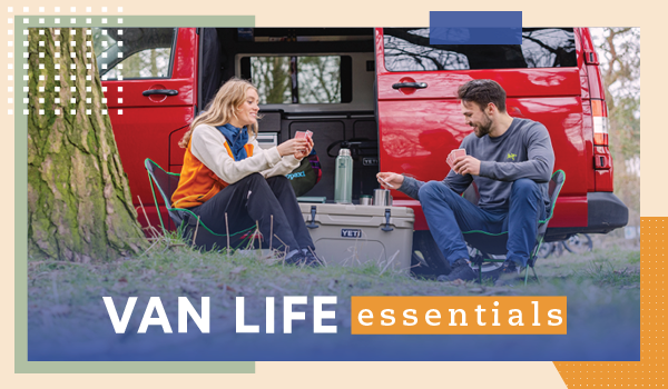 VAN LIFE ESSENTIALS. A man and woman play cards on top of a Yeti Tundra 45 Hard Cooler, a van parked behind them.