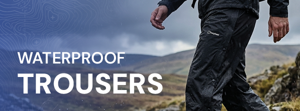 WATERPROOF TROUSERS. A man walks through a glen wearing Berghaus Men's Deluge 2.0 Pants. 
