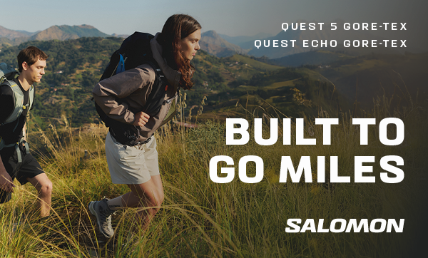 SALOMON QUEST 5 GORE-TEX AND QUEST ECHO GORE-TEX: BUILT TO GO MILES. Two hikers at the crest of a hill, wearing Salomon Quest GORE-TEX Walking Boots. 