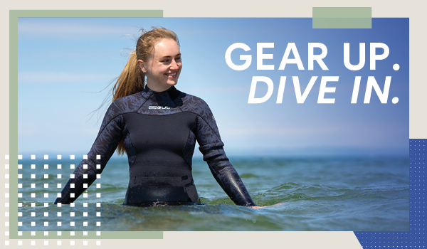 GEAR UP. DIVE IN.A woman waist-deep in the sea, wearing a Gul Women's Flexor 54 Yulex Steamer Wetsuit. 