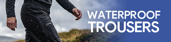WATERPROOF TROUSERS. A man walking, wearing Berghaus Men's Deluge 2.0 Waterproof Pants in Black.