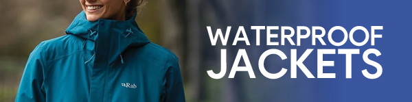 WATERPROOF JACKETS. A smiling woman wearing a Rab Women's Downpour Waterproof Jacket in Blue. 