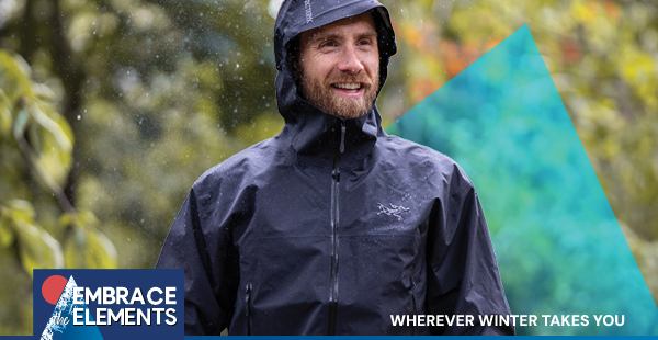 A smiling man walks in the rain, wearing an Arc'teryx Men's Beta SL Jacket in black with the hood up.