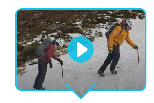 Trying a Winter Skills Course at Glenmore Lodge. A video still of a man and a woman ascending a mountain wearing Rab climbing gear. A blue play button sits in the centre of the image.