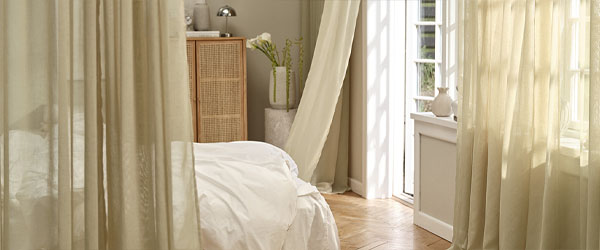 Egy világos hálószoba bézs színű függönyökkel