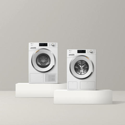 Miele TwinDos washer and dryer on white pedestal against gray background 