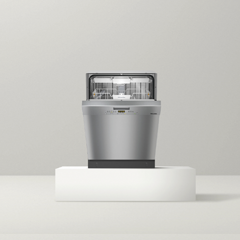 Miele dishwasher on white pedestal against gray background
