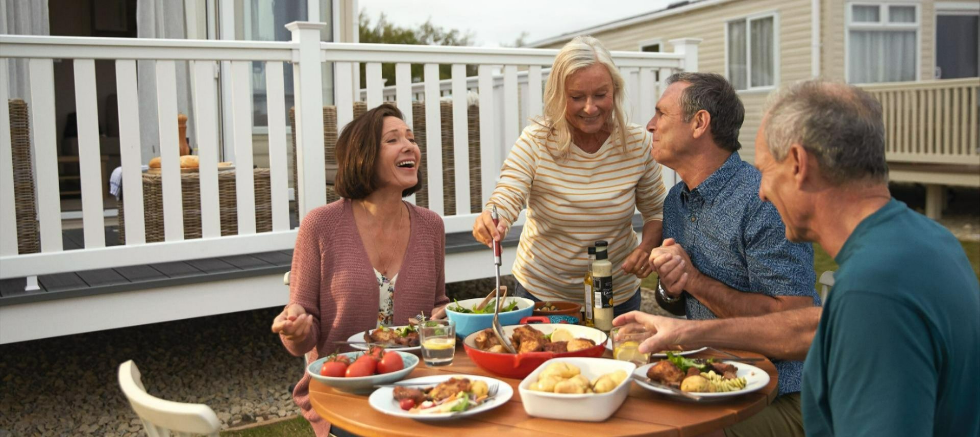Family and friends enjoying a meal outside a caravan