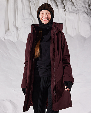 Vrouw in de sneeuw met een bordeaux kleurige jas aan van Elvine