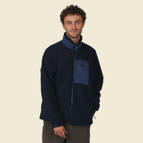 Persoon draagt een donkerblauwe fleece vest met opstaande kraag en borstzak.