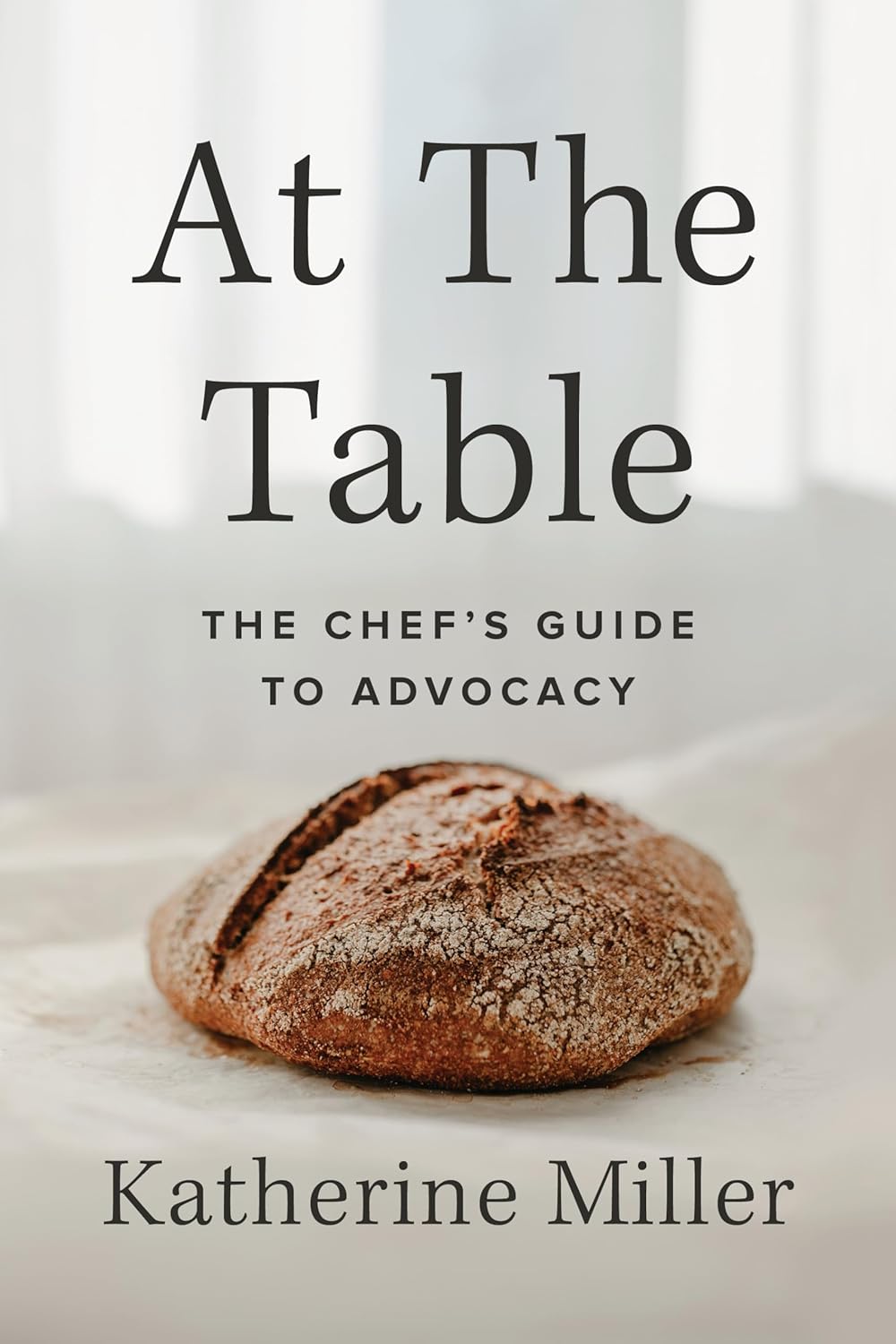 Book cover: At the Table: a Chef's guide to advocacy by Katherine Miller. The cover features an artisanal load of bread. 
