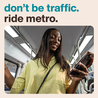 A person smiling while looking at their phone on the Metro with text that reads “don’t be traffic. ride metro.”