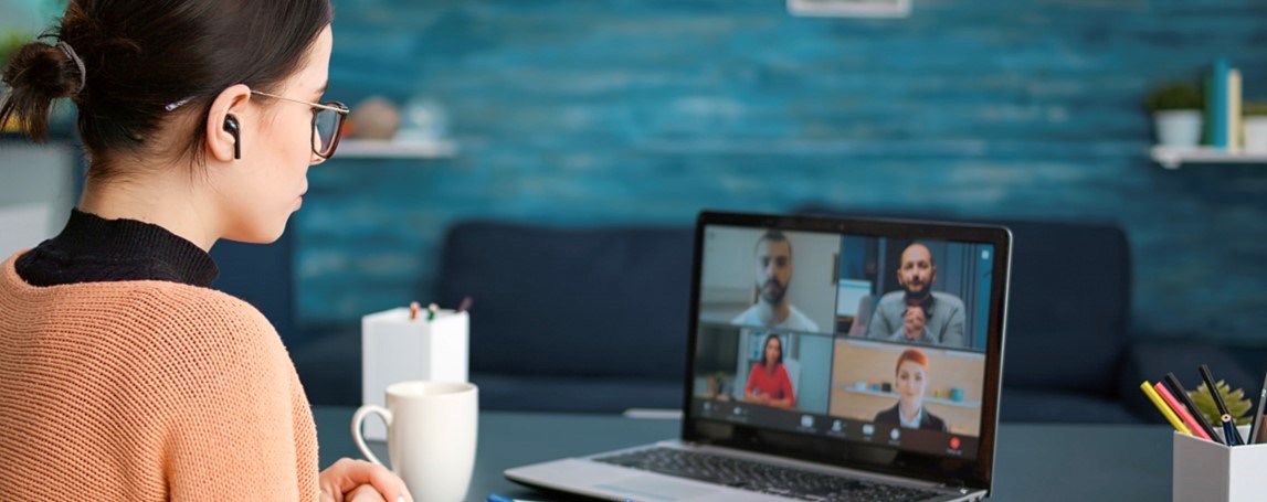 Femme devant son ordinateur et assistant à un webinaire.