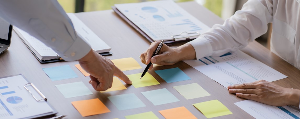 Des personnes pointent des post-it sur une table.