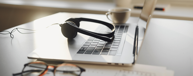Ordinateur portable sur un bureau avec des écouteurs, des lunettes et une tasse de café
