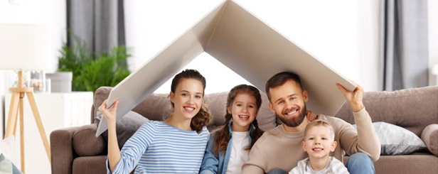 Famille assise dans un salon tenant un toit en carton