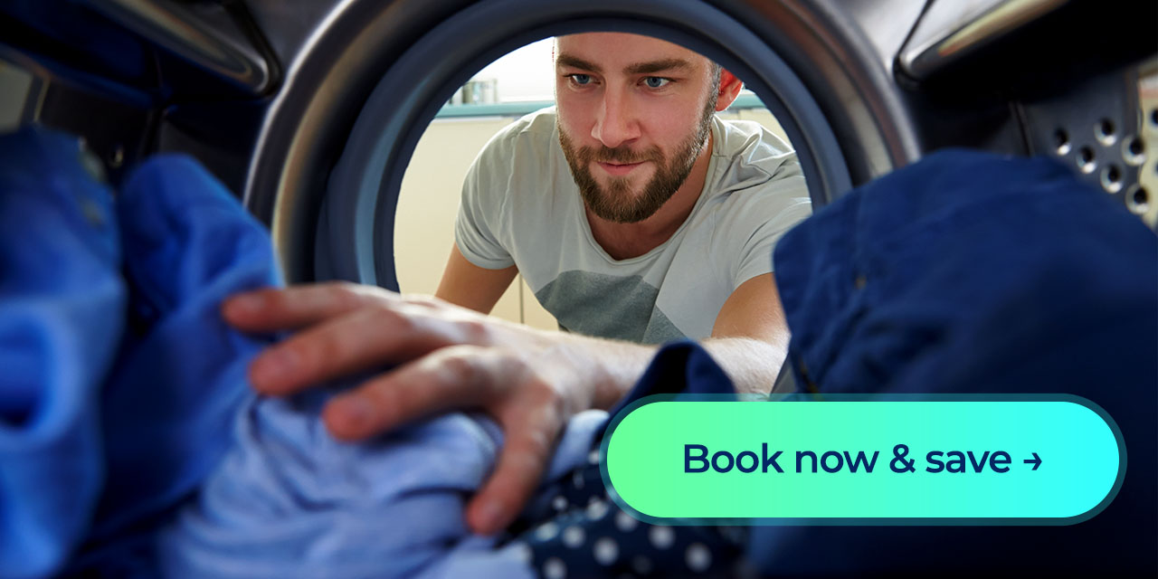 A man smiles as he reaches into his dryer for his clothes