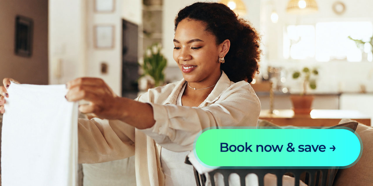 Smiling woman folds laundry beside a basket with a “Book now & save” button displayed.