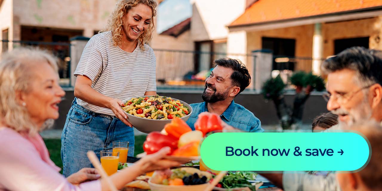 Woman serves pasta salad at an outdoor family meal with a “Book now & save” button.