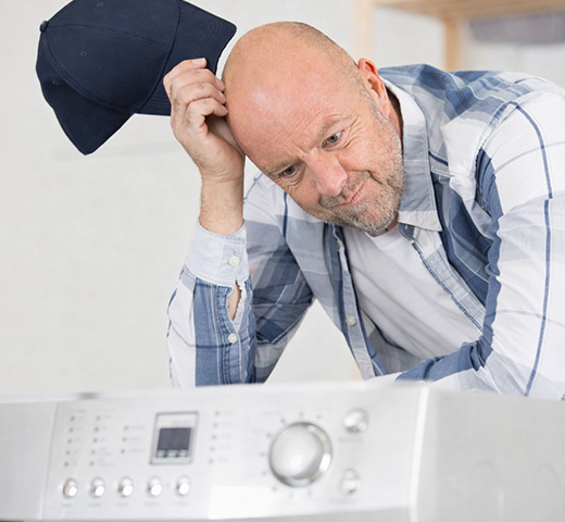 A man scratches his head as he looks over the dryer