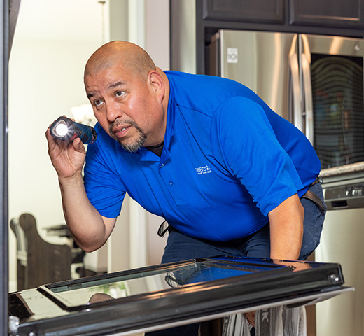 A Sears Home Services techinician looks in an oven
