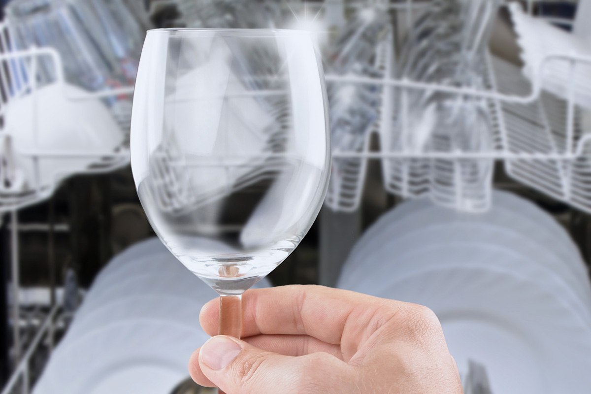 A crystal-clear wine glass being removed from a dishwasher