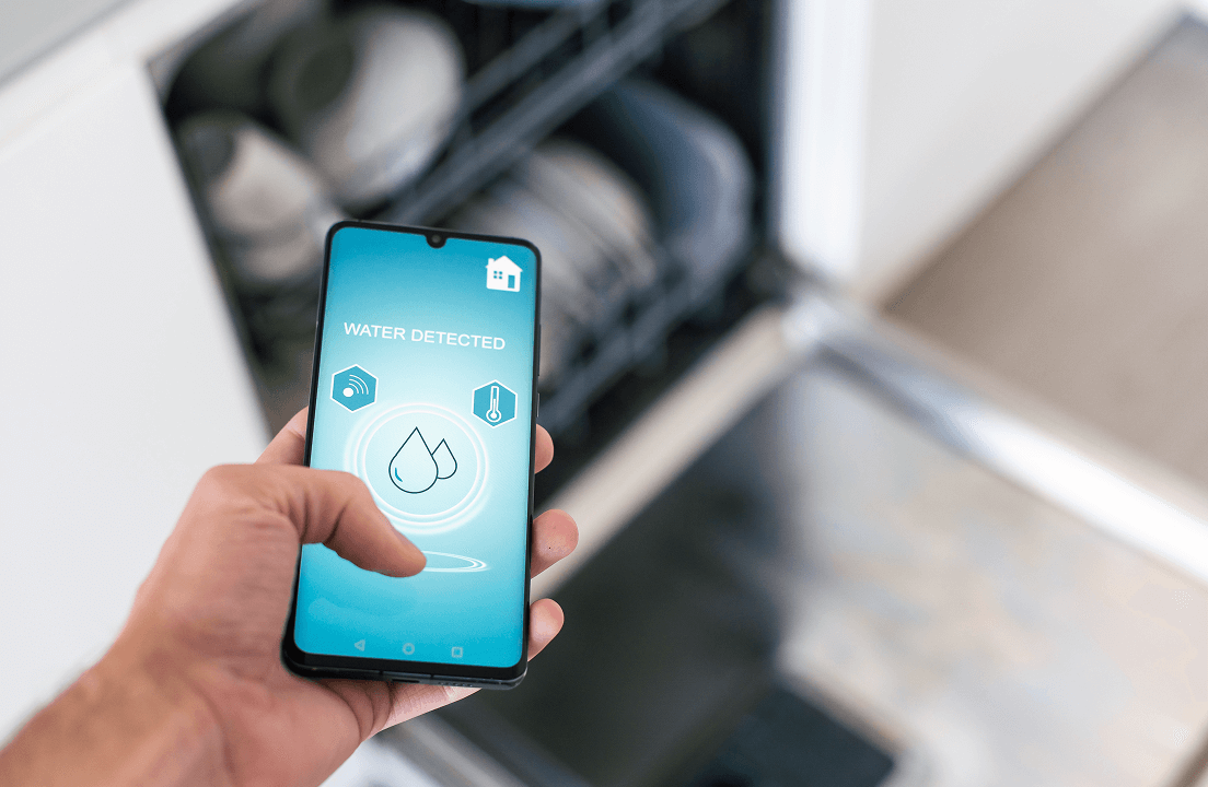A person looking at a phone that says 'water detected' on an app