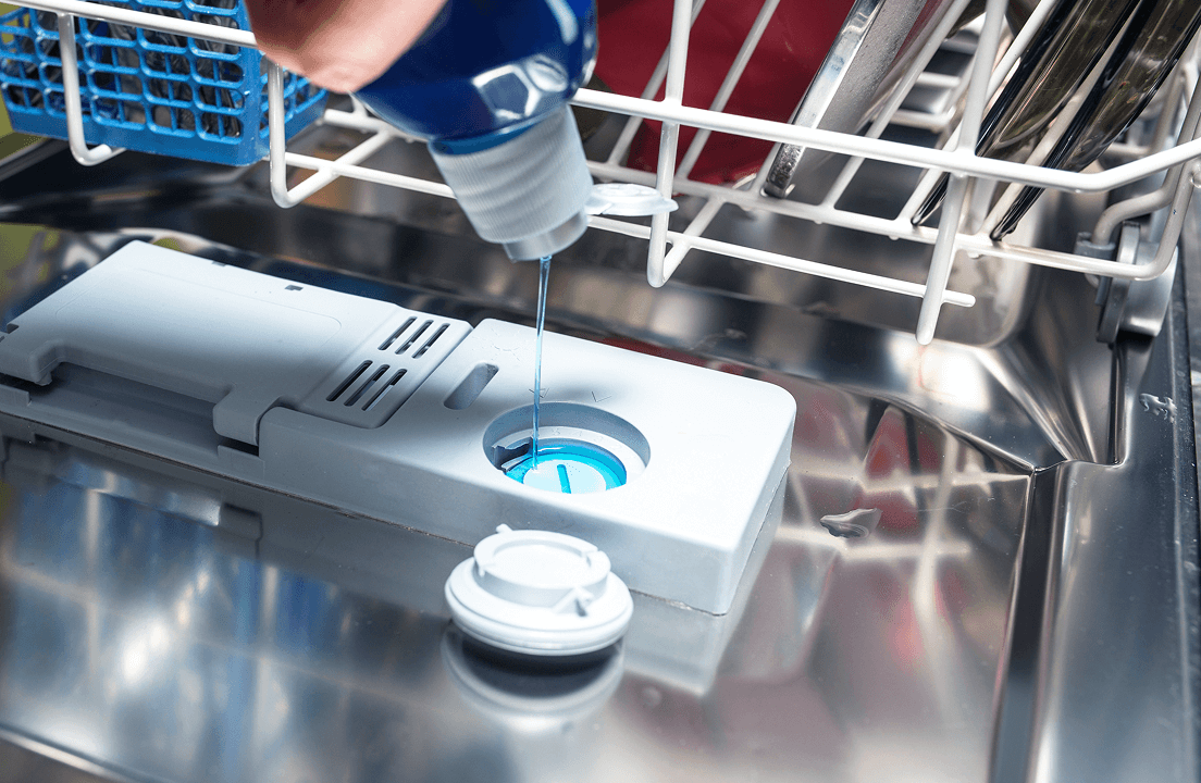 A person pouring in dishwashing liquid into a dispenser