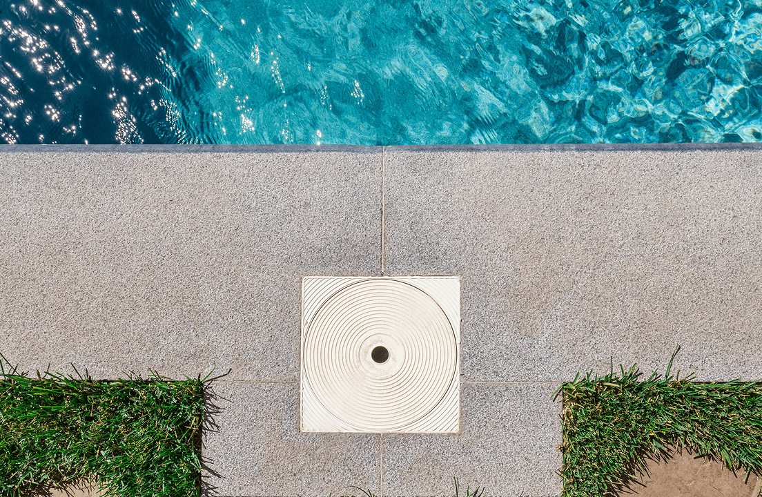 A top pool filter opening surrounded by concrete