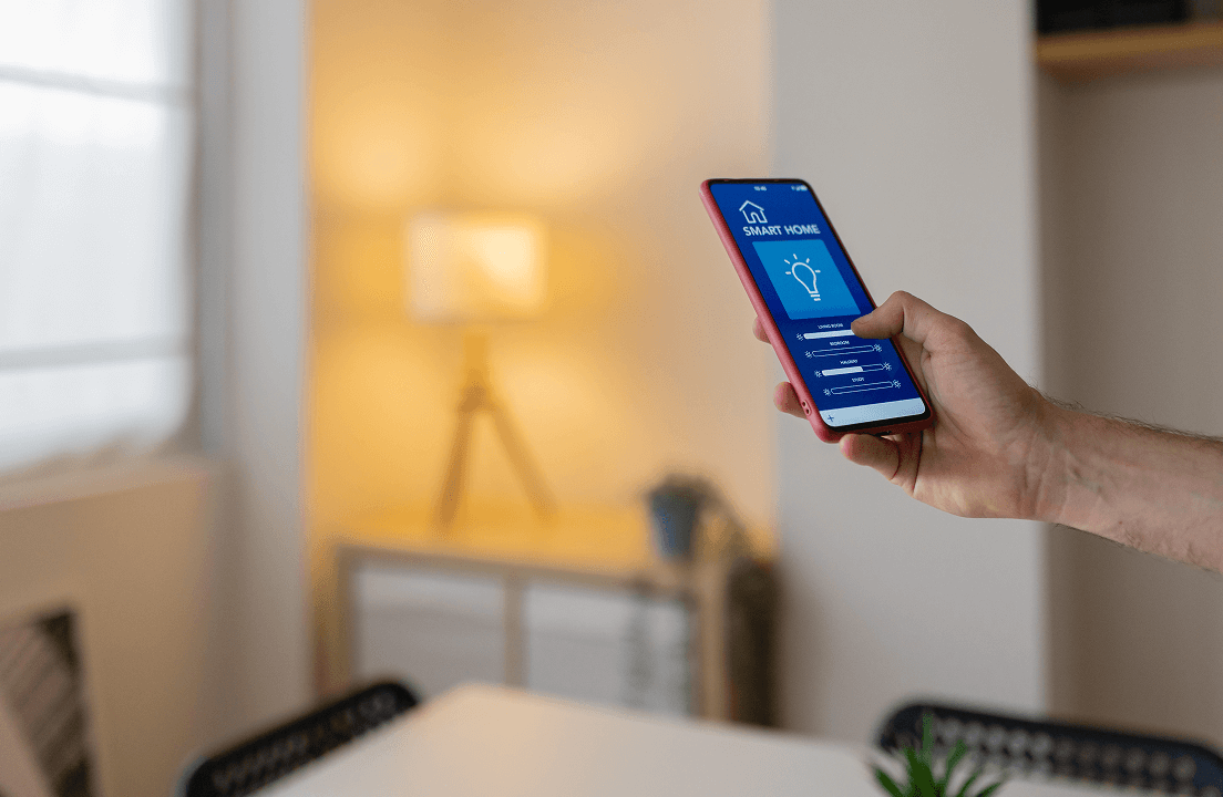 A person using their smart phone to turn on the lights within their home